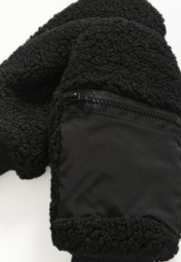 Mănuși negre dintr-un material plușat, cu un buzunar neted, negru, cu fermoar. Manșetă tricotată pentru un plus de căldură, având o suprafață moale și texturată.