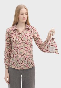 Blomster-mønstret skjorte i beige med røde og grønne designs, med knapper og lange ærmer; holder en matchende trækkesæk.