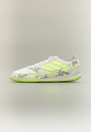 Weißer und neongelber Hallenfußballschuh mit Tarnmuster und drei gelben Streifen an der Seite.