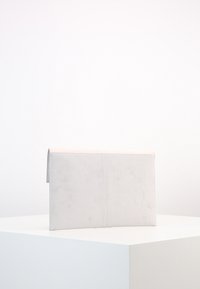 Jasnoszara kopertówka ze skóry zamszowej o gładkiej fakturze, prostej prostokątnej formie i klapie złożonej na górze. Prosty design bez ozdób.