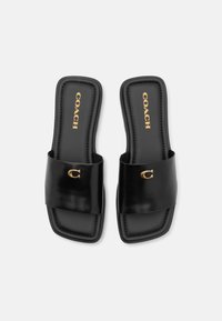Sandale negre de tip slide, fabricate din piele netedă, cu o curea lată și detalii cu logo-ul auriu embosat. Talpă plată cu accente cusute.