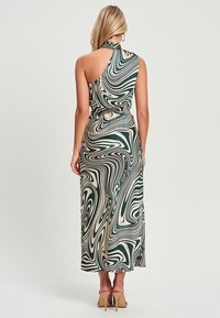 Vestido maxi en patrón de mármol verde y crema; diseño de cuello halter; cintura ajustada; textura de tejido suave; largo hasta los tobillos con detalle de espalda descubierta.