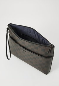 Mørkebrunt clutchbag med sjakkmønster og teksturert overflate, glidelås og håndleddsstropp. Innvendig har den et marineblått stofffôr.
