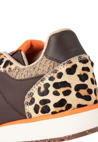 Zapatilla con un Upper sintético marrón, un lateral con patrón de leopardo, acentos texturizados en color beige y detalles en naranja en la suela. Tapa del talón marrón.