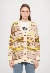 Πλεκτό cardigan σε κρεμ απόχρωση με πολύχρωμα κυματιστά σχέδια σε καφέ, ροζ και κίτρινο. Διαθέτει V λαιμόκοψη, πέντε κουμπιά και επώνυμη ετικέτα στο τελείωμα.