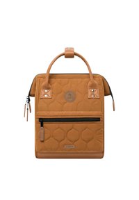 Gequilted tan rugzak met een afgeronde handgreep, zwarte ritszak en tan leren accenten. Beschikt over een cirkelvormig logo en een gestructureerd oppervlak.