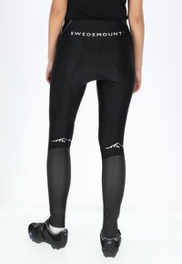 Black cycling leggings with a high waistband featuring "SWEDEMOUNT" in white. Textured panels and a padded area for comfort.