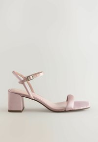 Sandal roz din satin, cu vârf pătrat, curea lată în față, curea pentru gleznă cu cataramă și toc bloc. Textură netedă, cu detalii minime.