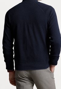 Navy gebreide pullover met een hoge kraag, geribbelde manchetten en zoom. Voorzien van een gestructureerd patroon en raglanmouwen.