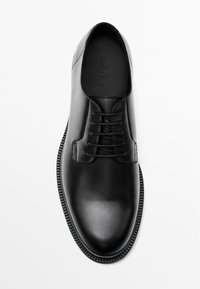 Black leather dress shoe featuring a smooth texture, traditional lace-up design, rounded toe, and a slim, textured sole.