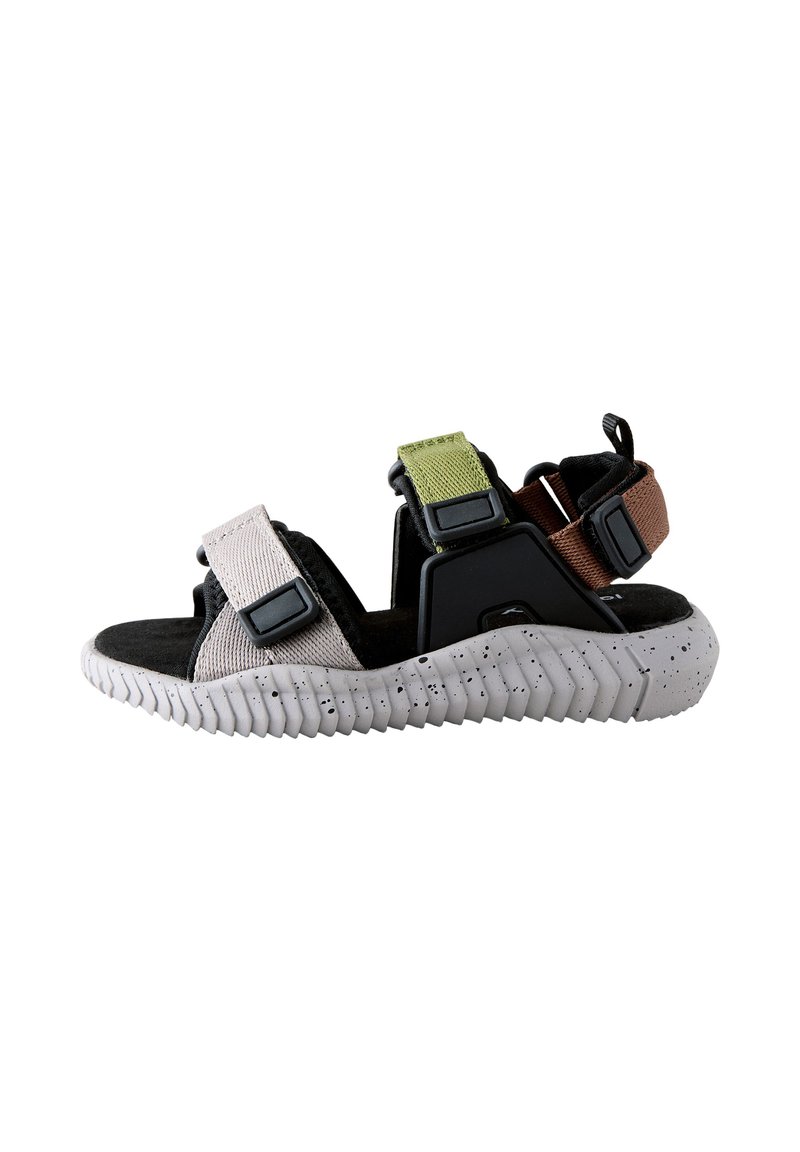 Sandales de sport avec une tige en tissu noir et gris, des sangles colorées vertes et marron, et une semelle blanche texturée tachetée.