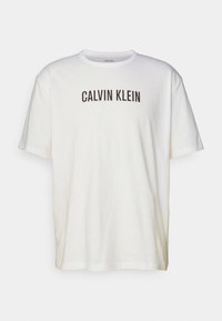 Biała bawełniana koszulka z krótkim rękawem i okrągłym dekoltem, z napisem "CALVIN KLEIN" wytłoczonym dużymi czarnymi literami na klatce piersiowej.