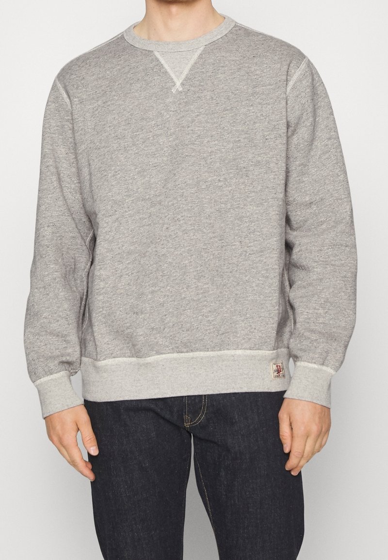 Gray sweatshirt made of cotton blend fabric, featuring ribbed cuffs and hem, round neck, and a small logo tag on the lower hem.