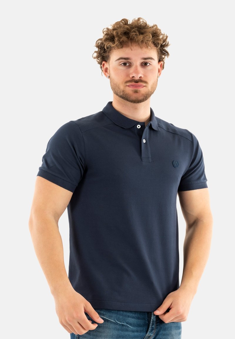 Polo de color azul marino hecho de una tela suave y texturizada; presenta un collar clásico, una tapeta de dos botones y un logotipo en el pecho.