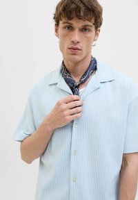 Blauw-wit gestreepte korte mouwen shirt met een camp collar, gecombineerd met een gedrukt marineblauw sjaaltje om de nek, wat een casual uitstraling geeft.