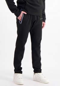 Zwarte sweatpants met een taps toelopende pasvorm, voorzien van zijzakken, blauwe accenten op de ritsen van de zakken en zachte, gestructureerde stof.