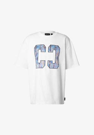 Maglietta bianca oversize a maniche corte con grandi lettere stilizzate "CO" in un motivo astratto blu e viola sul davanti.