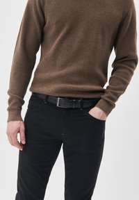 Barna textúrájú pulóver, fekete öv fém csattal és fekete nadrág. A hangsúly a testhezálló fazonokon és az ellentétes színeken van.