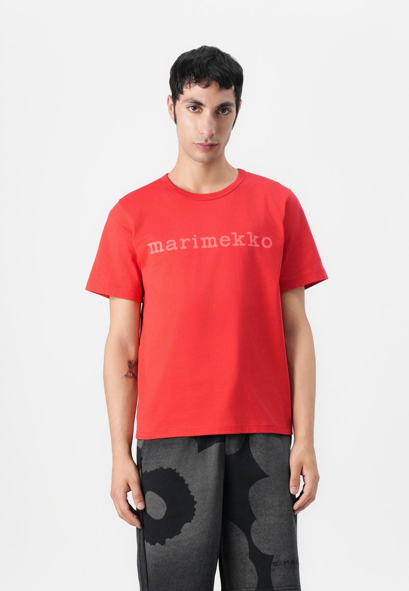 Červené bavlněné tričko s kulatým výstřihem a nápisem "marimekko" v světle šedém potisku na hrudi. Jednoduchý design.
