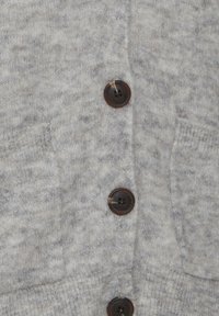 Cardigan en tricot gris avec un tissu texturé, quatre boutons marron foncé et deux poches frontales.
