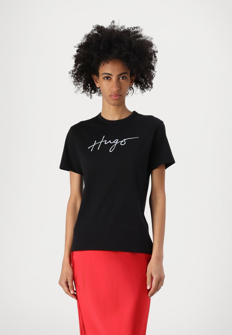 Black short-sleeve t-shirt featuring a white cursive "Hugs" graphic on the front, paired with a bright red, smooth-textured skirt.