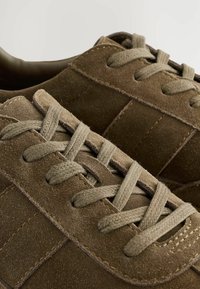 Braune Wildleder-Sneaker mit tonal abgestimmten Nähten und strukturierten Oberflächen. Verfügt über flache Schnürsenkel und verstärkte Ösen für zusätzliche Haltbarkeit.