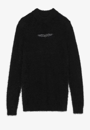 Czarny, puszysty sweter wykonany z wysokopilej tkaniny. Posiada okrągły dekolt oraz subtelny biały emblemat na piersi. W zestawie długie rękawy.