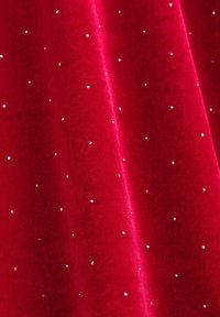 Czerwona aksamitna tkanina o gładkiej teksturze, z wzorem małych, błyszczących srebrnych kropek równomiernie rozmieszczonych na powierzchni.