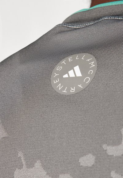 Gray fabric with a textured surface, featuring a circular logo with a white icon on the upper back, complemented by a teal accent.