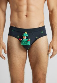 Czarne majtki z zielonymi wzorami choinek, z pluszowym pingwinem w kostiumie choinki jako wyraźnym elementem z przodu.