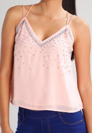 Top sin mangas de color rosa con escote en V, que presenta lentejuelas plateadas y cuentas a lo largo del escote, hecho de una tela ligera.