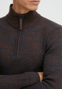 Langärmliger Pullover mit Reißverschlusskragen in dunkelblau und braunem Strukturstrick. Verfügt über einen hohen Kragen und gerippte Bündchen mit einem Logotag in der Nähe des Reißverschlusses.