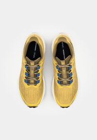 Yellow running shoes with a textured upper, blue and brown accents, and patterned laces. Features a white midsole and a black insole.