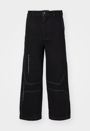 Sorte brede jeans lavet af denim, med kontrasterende hvid syning og geometriske paneldetaljer. Knappen foran med lukkefunktion og lommer.