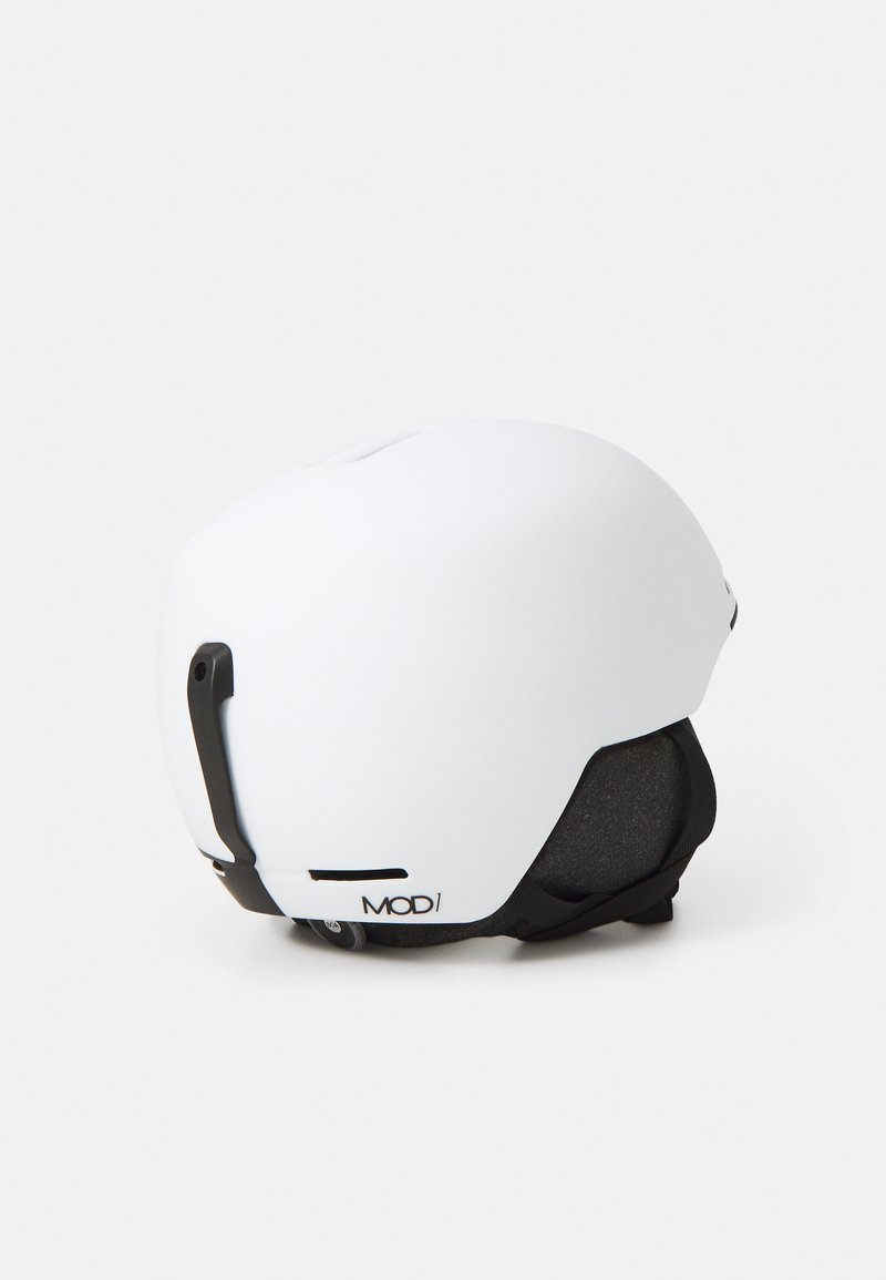 Weißer Skihelm mit matter Oberfläche. Verfügt über einen schwarzen Riemen, ein verstellbares Visier und Belüftungslöcher für Luftzirkulation.