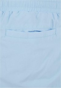 Light blue fabric with a soft texture, featuring an elastic waistband and a back pocket with a rectangular opening.