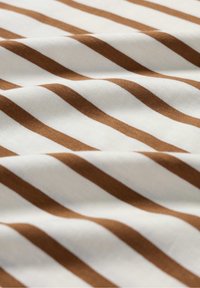 Katoenen stof met afwisselend bruine en witte strepen, met een gladde textuur en een diagonale val die patroon details onthult.
