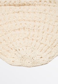 Borsa all'uncinetto di colore avorio con forma circolare, caratterizzata da un motivo testurizzato e un design a intreccio aperto. Materiale in morbido cotone.