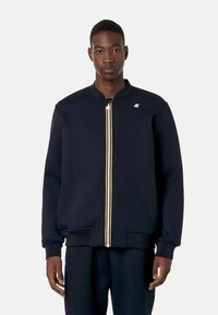 Felpa zip-up blu navy con colletto rotondo, tasche laterali, zip frontale con accenti gialli e bianchi e logo sul lato sinistro del petto.