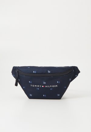 Hajózási anyagból készült tárolózsák, fehér zászlók mintával, cipzáras záródással és "TOMMY HILFIGER" logóval az elején. Kompakt, háromszög alakú.