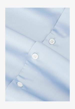 Camisa de satén azul claro con textura suave, con cierres de botones blancos y mangas dobladas. Diseño minimalista sin patrones.