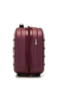 Valigia rigida di un profondo bordeaux, con un'esterno testurizzato e scanalature orizzontali, chiusura a doppia zip e quattro ruote per la mobilità.