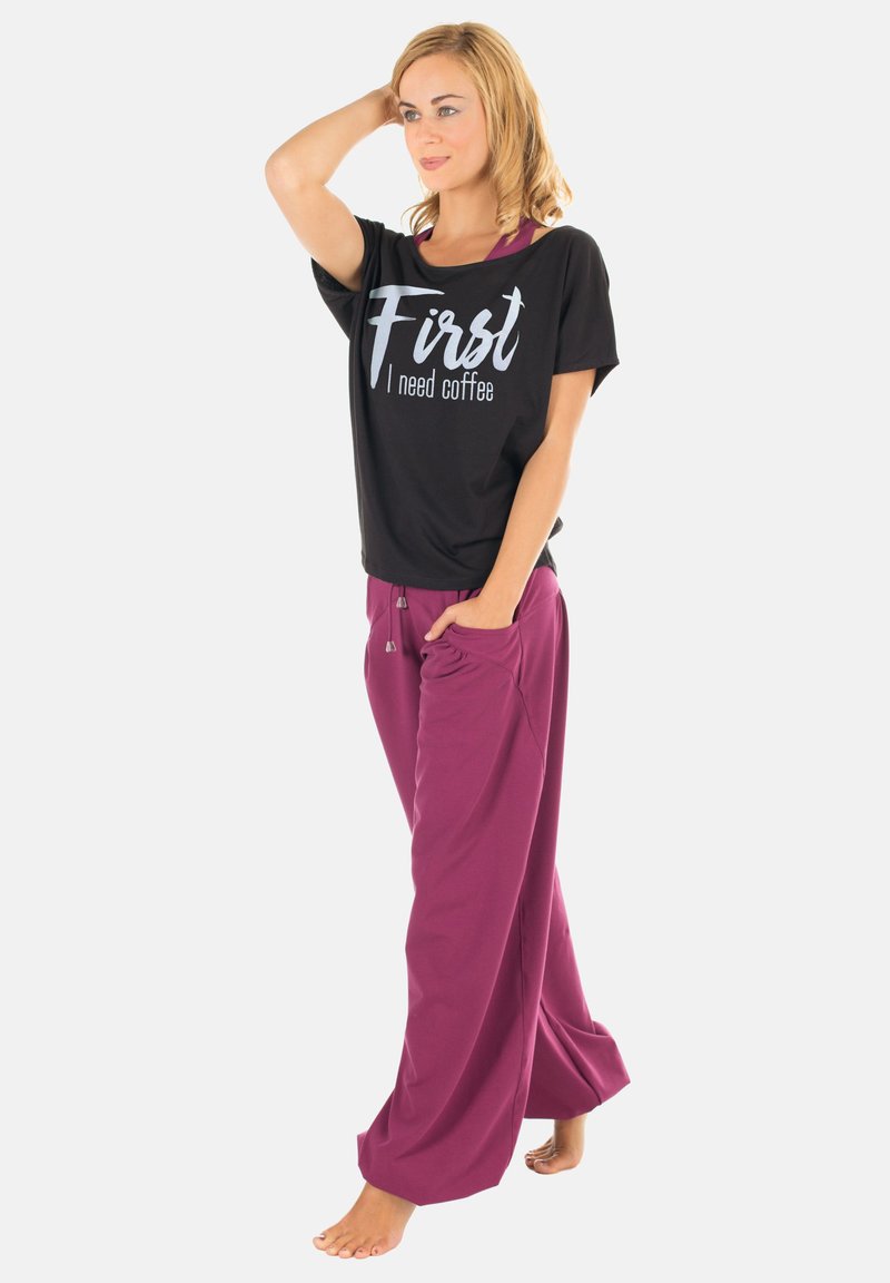 Black t-shirt with white text "First I need coffee," paired with loose-fitting maroon pants. Soft fabric, relaxed design, and side pockets.