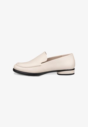 Mocassins en cuir beige avec un bout arrondi, des coutures minimales et un petit talon noir. Texture lisse avec une finition polie.