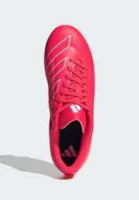 Scarpa da calcio sintetica rossa con accenti bianchi, caratterizzata da una superficie liscia, chiusura con lacci e un logo distintivo sulla linguetta e sulla soletta.
