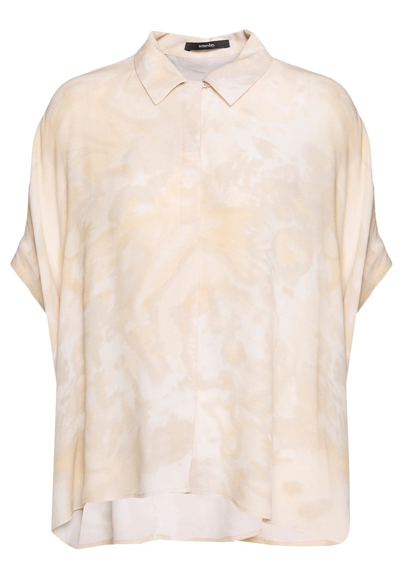 Ljusbeige kortärmad skjorta med en mjuk textur, med en knapp-ner krage och ett subtilt abstrakt mönster över hela.