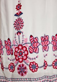 Weißer Stoff mit lebendiger roter und pinker floralem Stickerei. Beinhaltet komplexe Muster mit kreisförmigen und Blätterdesigns entlang des Saums.
