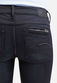 Svarta denimjeans med slim fit, detaljerade med dragkedjefickor och två bakfickor med en subtil böjd sömdesign.