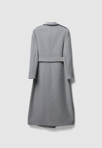 Long manteau en laine grise à la texture lisse, coupe cintrée, avec une ceinture à la taille. Il présente un col et des manches longues, sans quincaillerie visible.