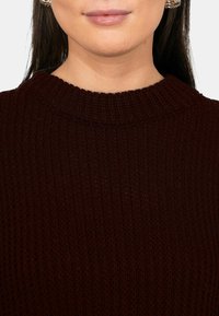 Maglione bordeaux a coste con collo alto, caratterizzato da una superficie testurizzata e senza motivi o elementi visibili.